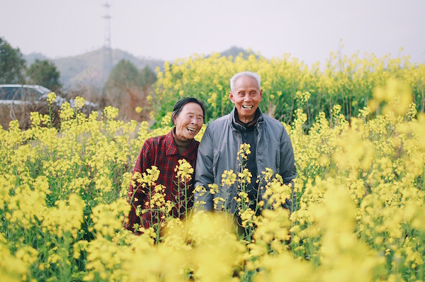 old Asian couple laughing in flowers